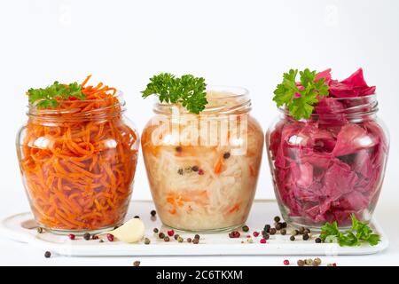 Fermentierte und konservierte vegetarische Lebensmittel Konzept. Sauerkraut, marinierter Rotkohl und Karotte in offenen Glasgefäßen auf Keramikplatte Stockfoto