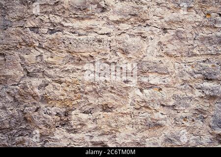 Beige und braune Natursteinwand als Textur oder als Hintergrund. Stockfoto
