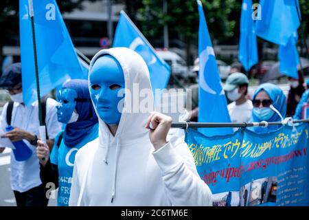 Tokio, Japan. Juli 2020. Aktivisten mit Masken in ostturkestanischen Flaggen-Farben gesehen mit der Flagge "Befreien Hongkong, Revolution unserer Zeit" während der Proteste.Hongkong und Uiguren Pro-Demokratie-Demonstranten gingen auf die Straßen in Yoyogi, Marschieren durch die belebten Straßen Shibuya und Harajuku, um gegen China gegen das neue nationale Sicherheitsgesetz von Hongkong und das Massaker an den Uiguren in der chinesischen Provinz Xinjiang zu protestieren. Kredit: SOPA Images Limited/Alamy Live Nachrichten Stockfoto