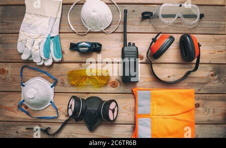 Arbeitsschutzausrüstung flach legen. Industrielle Schutzausrüstung auf Holzhintergrund. Baustellenkonzept Gesundheit und Sicherheit, Draufsicht. Stockfoto