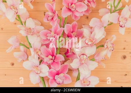 Bündel von künstlichen blühenden Orchideenblumen auf hölzernen Hintergrund. Inneneinrichtung. Stockfoto