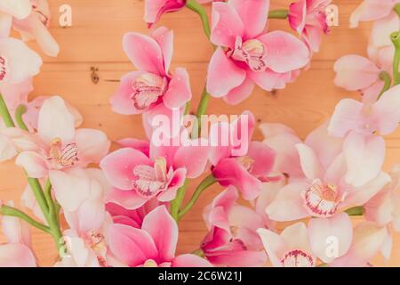 Bündel von künstlichen blühenden Orchideenblumen auf hölzernen Hintergrund. Inneneinrichtung. Stockfoto