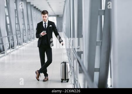 Urban Business Mann SMS auf Handy im Flughafen Stockfoto