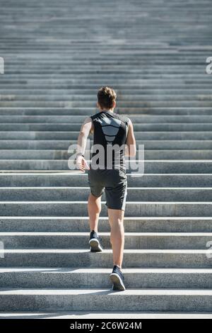 Treppen hochlaufen. Mann in Sportbekleidung und mit Fitness Tracker zur Hand, geht in den Sport Stockfoto