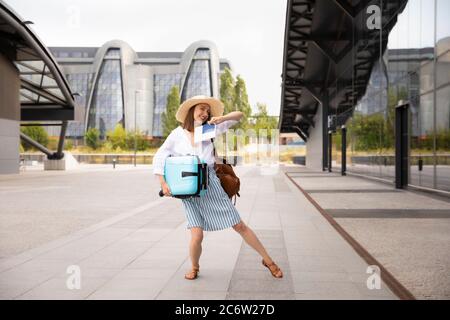Bild von aufgeregt junge hübsche Frau Tourist posiert. Frau mit Koffer mit Pass und Tickets. Das Mädchen genießt den Urlaub. Stockfoto