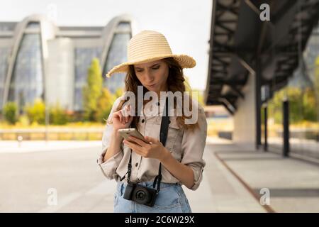 Bild von aufgeregt junge hübsche Frau Tourist posiert. Eine Frau mit einem Koffer steht am Bahnhof, sie kommuniziert mit jemandem am Telefon. Stockfoto