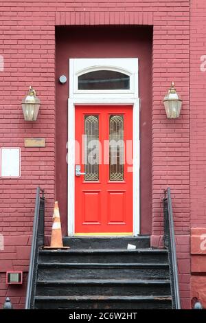 Rote vintage hölzerne Eingangstür mit Kombinationsschloss, weißem Rahmen und segmentalem Bogen. New Jersey. USA. Stockfoto