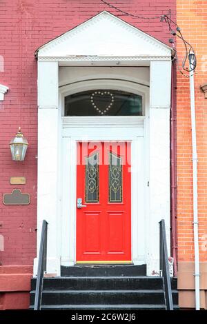 Rote vintage hölzerne Eingangstür mit Kombinationsschloss, weißem Rahmen und segmentalem Bogen. New Jersey. USA. Stockfoto