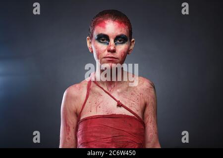 Foto junge Frau in gefälschtem Blut auf grauem Hintergrund Stockfoto