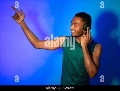 Afrikanischer Sportsman In Ohrhörer Tanzen Musik Genießen Auf Blauem Hintergrund Stockfoto