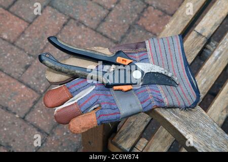 Ein Paar Gartenschere und ein Gartenhandschuh auf einer Gartenbank in Großbritannien, Frühjahr 2020 Stockfoto