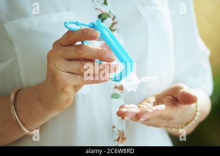 Leben während der covid-19 Pandemie. Nahaufnahme der Frau in weißer Bluse, die Hände mit Desinfektionsmittel desinfiziert. Stockfoto