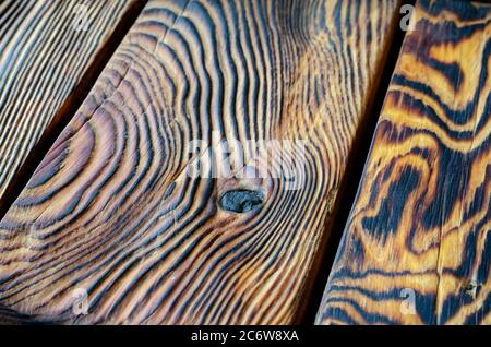 Gebrannter gebürsteter Holzhintergrund. Detailreiche Aufnahme von Kiefernbrettern in dänischem Öl getränkt. Tischlerei, Zimmerei. Selektiver Fokus. Stockfoto