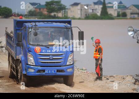 Poyang, Chinas Provinz Jiangxi. Juli 2020. Mitarbeiter arbeiten auf der Baustelle eines durchbrechten Deichs in der Stadt Poyang im Landkreis Poyang, ostchinesische Provinz Jiangxi, 12. Juli 2020. Der Flussufer in der ostchinesischen Provinz Jiangxi wurde am späten Mittwoch nach fortwährenden sintflutartigen Regenfällen durchbrochen, was über 9,000 Einwohner zur Evakuierung zwang. Quelle: Zhou Mi/Xinhua/Alamy Live News Stockfoto