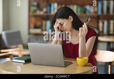 Augen Ermüden. Asiatische Mädchen Reiben Nasenbrücke Müde Nach Der Arbeit Auf Laptop Stockfoto