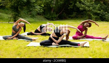 Wohlfühlkonzept. Hübsche junge Frauen, die Yoga-Übungen im Park machen Stockfoto