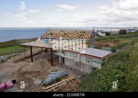 Das lang erwartete Dorfhaus im Bau in Ogmore am Meer mit seiner Stahlrahmenschale und neue hölzerne künstlerische Dachkonstruktion im Rahmen. Stockfoto