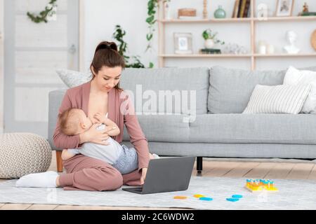 Junge Mutter Stillbaby Während Der Arbeit Auf Laptop Zu Hause Stockfoto