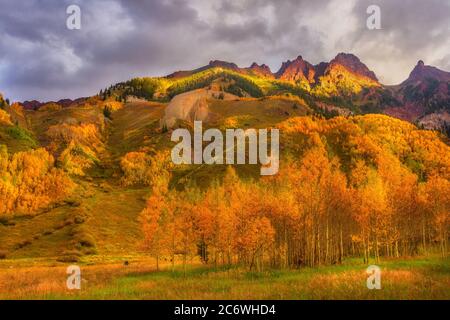 Die Aspen Blätter leuchten in der Morgensonne, während die Berggipfel aufleuchten, während die Sonne sie trifft Stockfoto