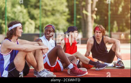 Diverse Millennial Athleten sprechen miteinander während ihrer Pause auf Outdoor-Basketballplatz, leeren Raum Stockfoto