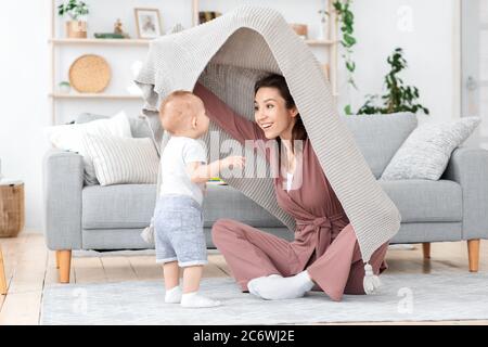 Glückliche Mutter Spielt Mit Kleinkind Sohn Zu Hause, Peeking Aus Unter Decke Stockfoto