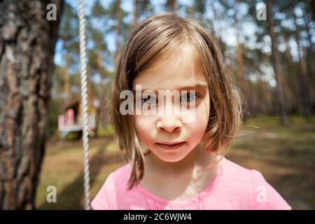 Liebenswert kleines Mädchen sitzt auf einer Schaukel und macht Gesichter Stockfoto