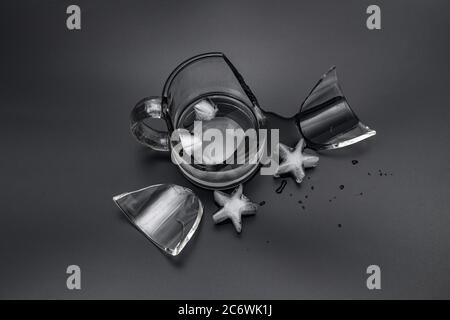 Zerbrochene Glasschale mit Wasser und Eis auf schwarzem Hintergrund Stockfoto