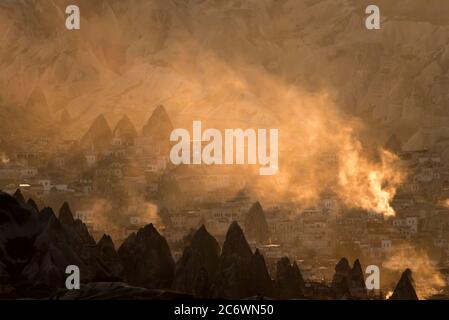 Malerischer Blick auf die Stadt in Rauch und Sonnenuntergang Lichter in Goreme, Kappadokien, Türkei. Stockfoto