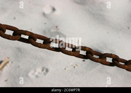 Ungenutzte rostige Kette am weißen Sandstrand Stockfoto