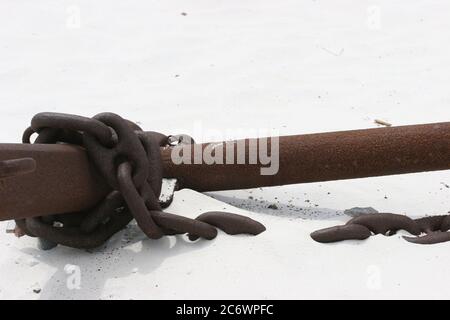 Rostige Kette um alten rostigen Ankerschacht am weißen Sandstrand gewickelt Stockfoto