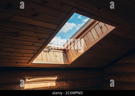 Natürliches Licht durch ein sauberes Fenster in der Decke auf der Dachschräge des Dachgeschosses - helles natürliches Licht und klarer Himmel Stockfoto