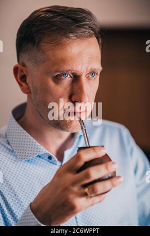 Ernster Mann mit einem strengen Blick - blaue Augen - trinkt Kalabash Mate Stockfoto