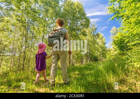 Mutter und Tochter wandern im Sommer durch den schönen grünen Wald Stockfoto