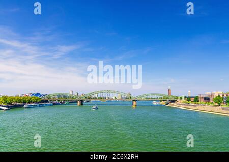 Die Hohenzollernbrücke oder Hohenzollernbrücke über den Rhein mit auf dem Wasser fahrenden Frachtschiffen, Fußgänger- und Eisenbahnstahlbrücke, Köln-Zentrum, Nordrhein-Westfalen, Deutschland Stockfoto