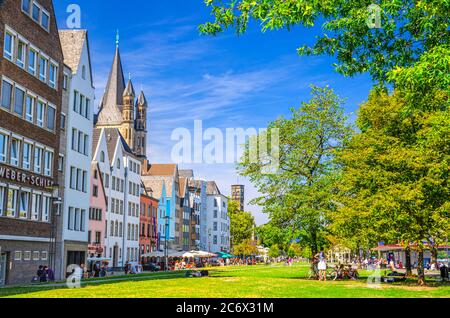 Köln, 23. August 2019: Typisch deutsche Häuser und Gebäude und grüne Rasenfläche mit Bäumen in der Nähe der Rheinpromenade in der Altstadt, Menschen Touristen, die eine Pause Stockfoto