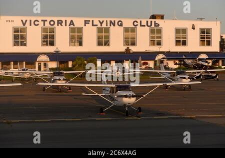 Kleine Einzelflugzeuge werden auf dem Asphalt vor dem Victoria Flying Club Gebäude am Victoria International Airport bei Sonnenuntergang in Sidney, Briti geparkt Stockfoto