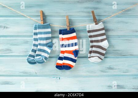 Baby gestreifte Socken auf einer Wäscheleine auf blauem Holzhintergrund Stockfoto