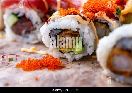 Japanische Küche, frisches Sushi oder Sashimi aus Reis mit Lachs, Avocado, Gurke, rotem Fischkaviar, Tempura-Garnelen aus nächster Nähe Stockfoto