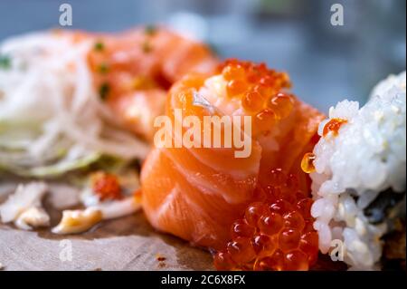 Japanische Küche, frisches Sushi oder Sashimi aus Reis mit Lachs, Avocado, Gurke, rotem Fischkaviar, Tempura-Garnelen aus nächster Nähe Stockfoto