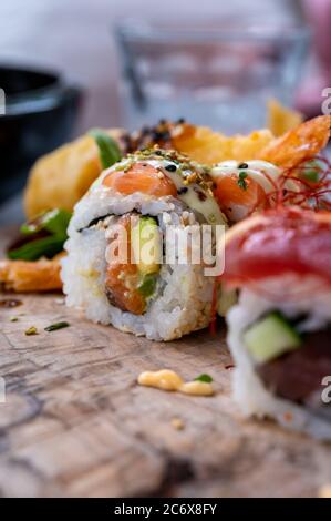 Japanische Küche, frisches Sushi oder Sashimi aus Reis mit Lachs, Avocado, Gurke, rotem Fischkaviar, Tempura-Garnelen aus nächster Nähe Stockfoto