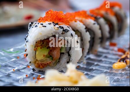 Japanische Küche, frisches Sushi oder Sashimi aus Reis mit Lachs, Avocado, Gurke, rotem Fischkaviar, Tempura-Garnelen aus nächster Nähe Stockfoto