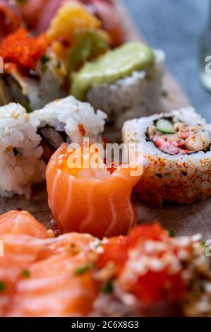 Japanische Küche, frisches Sushi oder Sashimi aus Reis mit Lachs, Avocado, Gurke, rotem Fischkaviar, Tempura-Garnelen aus nächster Nähe Stockfoto
