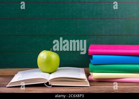 Apple und farbige Bücher auf dem schwarzen Brett Hintergrund, zurück zur Schule, Bildungskonzept Stockfoto