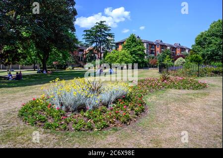 Bromley (Großraum London), Kent, Großbritannien. Queens Gardens in der Nähe des Einkaufszentrums Glades in Bromley. Hübsche Blumenbeete und Leute, die auf dem Rasen sitzen. Stockfoto