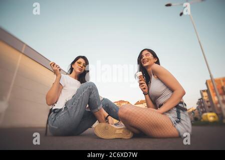 Zwei junge Freundinnen essen Eis auf dem Parkplatz Stockfoto