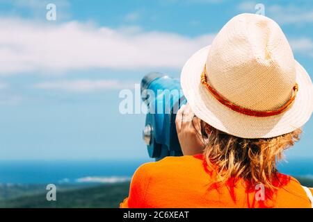 Ein Mädchen im Strohhut schaut durch ein Stadtfernglas. Konzept des Reisens. Stockfoto