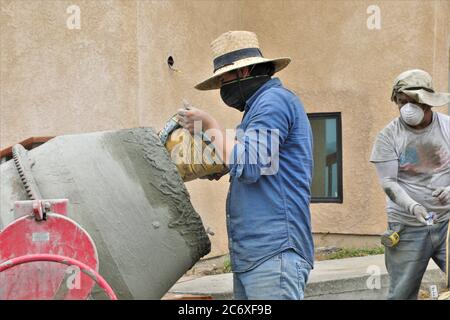 Mexikanische Arbeitskräfte bauen eine Zement Stützmauer mit Blick auf Morro Bay Mündung in Zentral-Kalifornien setzen Zement in Mischer für Fugen Stockfoto