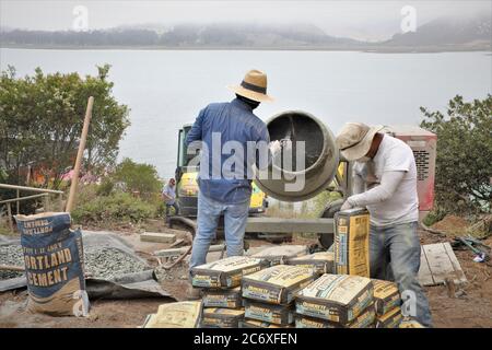 Mexikanische Arbeitskräfte, die eine Zement Stützmauer mit Blick auf Morro Bay Mündung in Zentral-Kalifornien missing Zement Stockfoto