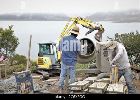 Mexikanische Arbeitskräfte, die eine Zement Stützmauer mit Blick auf Morro Bay Mündung in Zentral-Kalifornien missing Zement Stockfoto