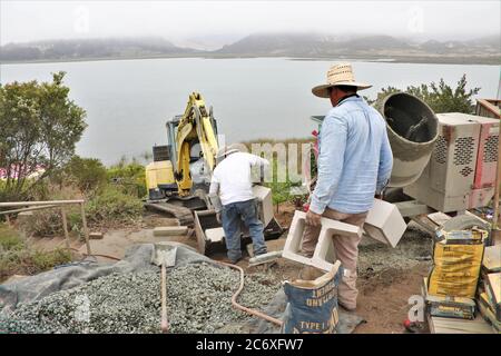 Mexikanische Arbeiter bauen eine Zementmauer mit Blick auf Morro Bay Mündung in Zentral-Kalifornien Stockfoto